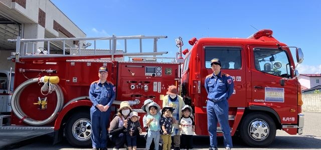 消防車の前で記念撮影する子どもたちと消防署員